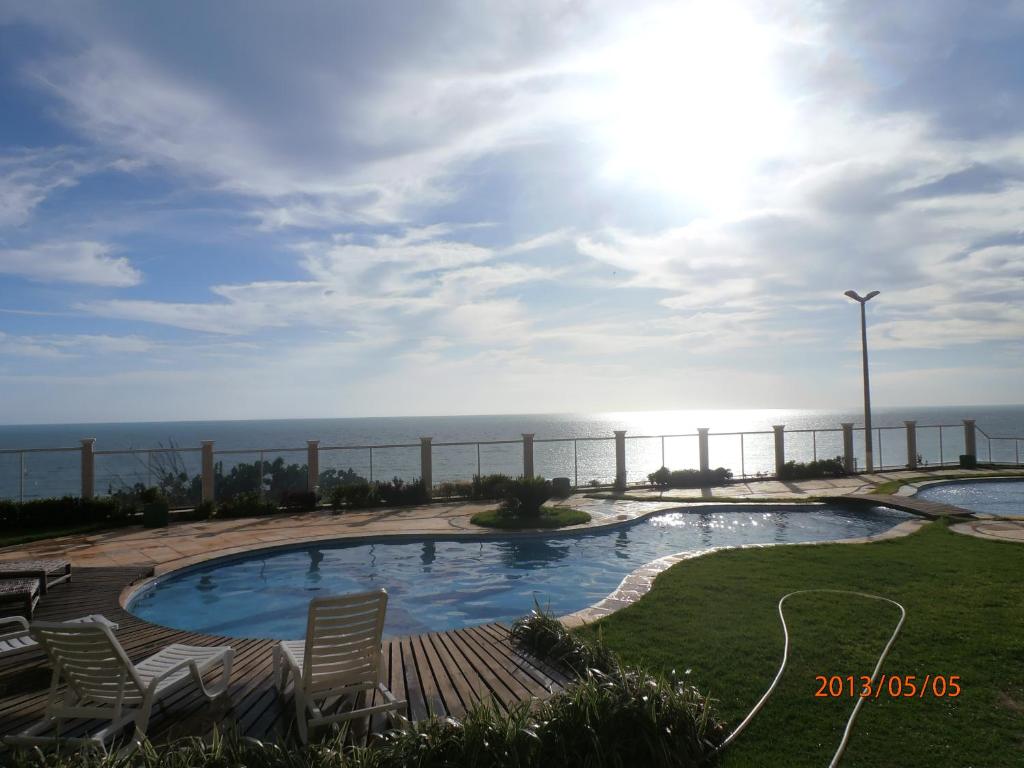 卡诺格布拉达卡诺阿魁布拉达公寓的一个带椅子的游泳池,背景是大海