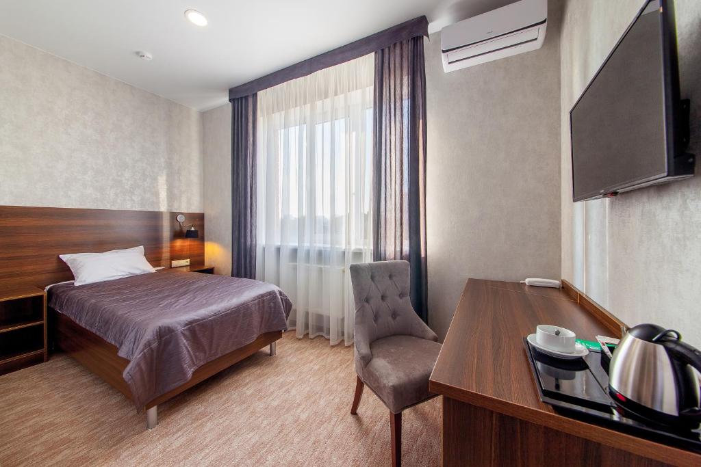 克拉斯诺达尔D Hotel的配有一张床、一张桌子和一张桌子的酒店客房