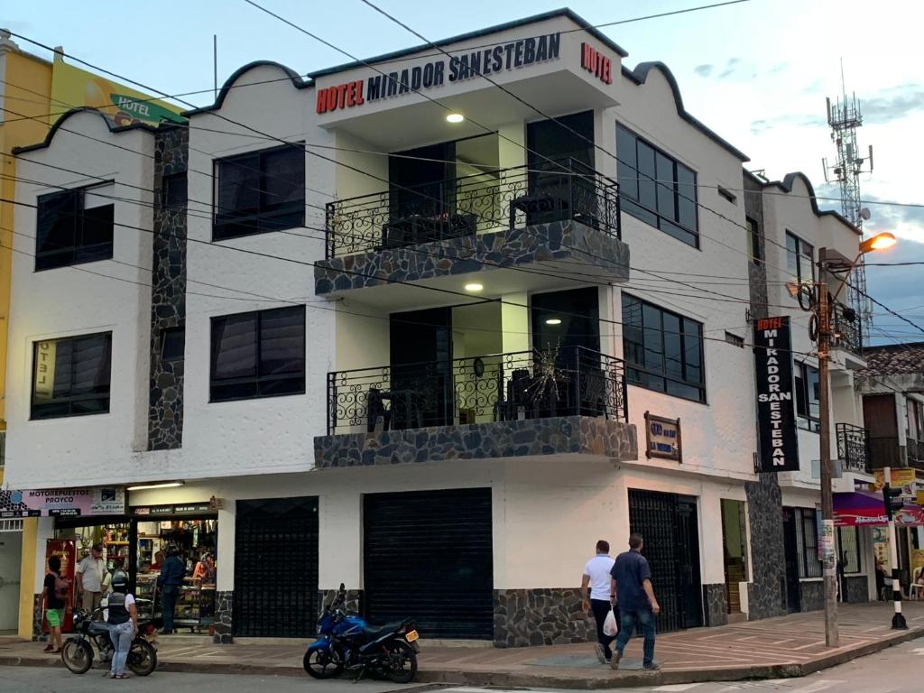 拉特瓦伊达Hotel Mirador San Esteban的一座白色的建筑,前面的人在步行