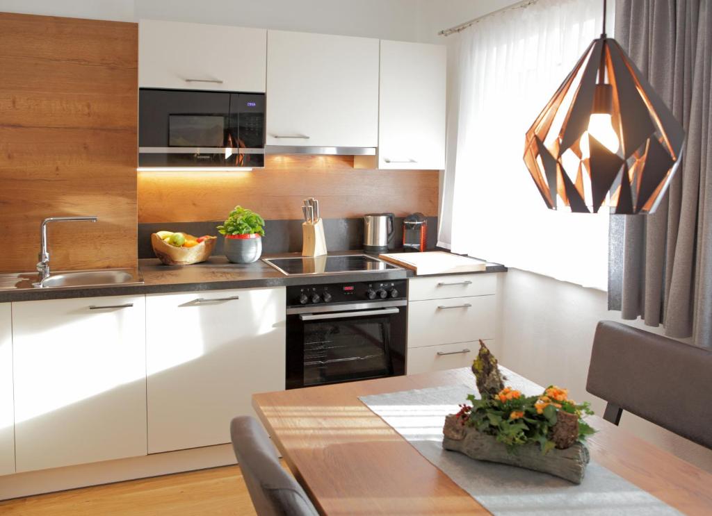 阿尔滕马克特蓬高Appartementhaus Reiter Village Room的厨房配有白色橱柜和木桌