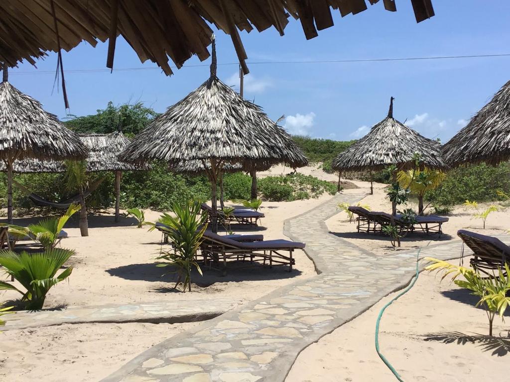 MambruiMambrui Golden Beach Bar and Cottages的沙滩上带椅子和草伞的海滩