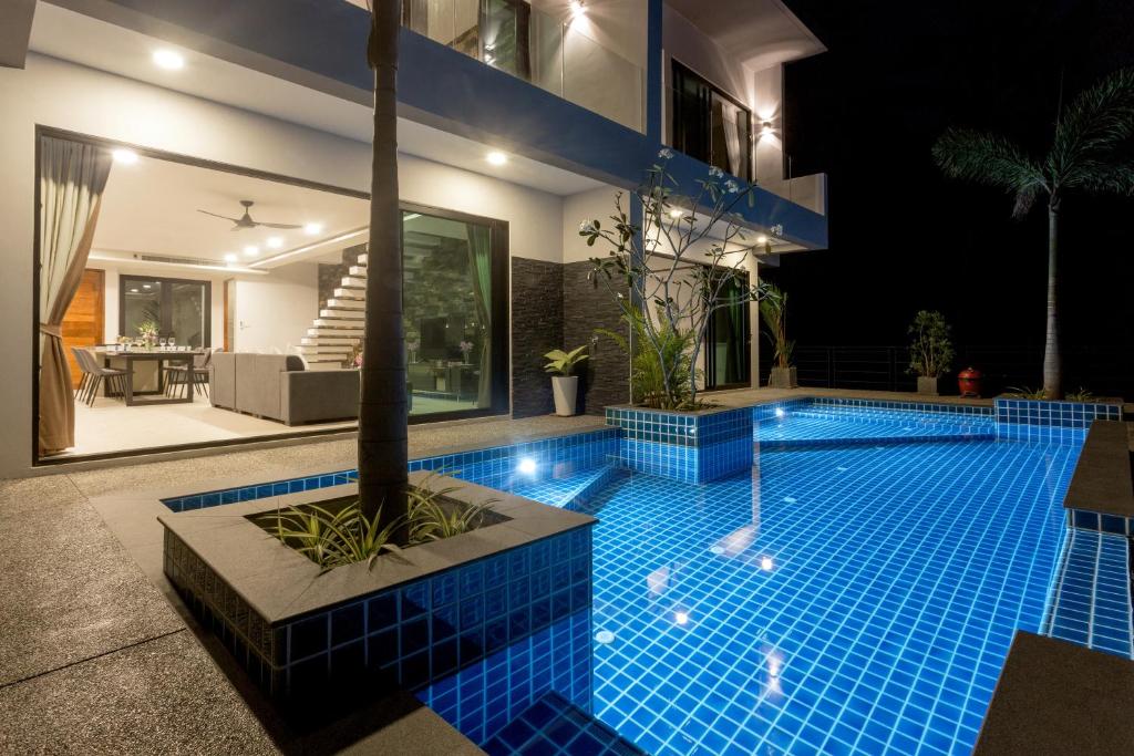 卡塔海滩Twin Villas Seaview Kata的夜间房子中间的一个游泳池