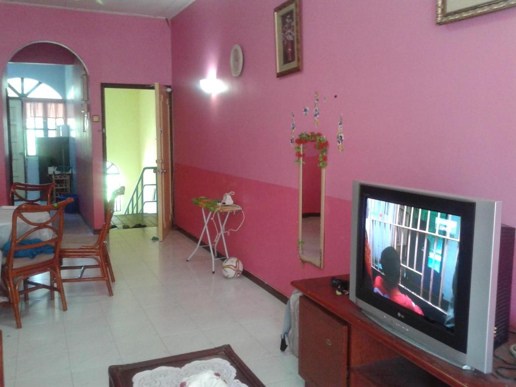 瓜埠Seri Lagenda Apartment的一间带电视和粉红色墙壁的客厅