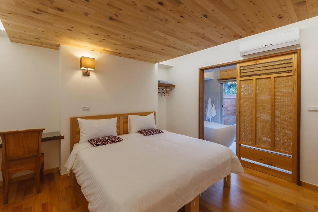 Yung-an-ts'un后山人家民宿A馆的卧室设有白色的床和木制天花板。