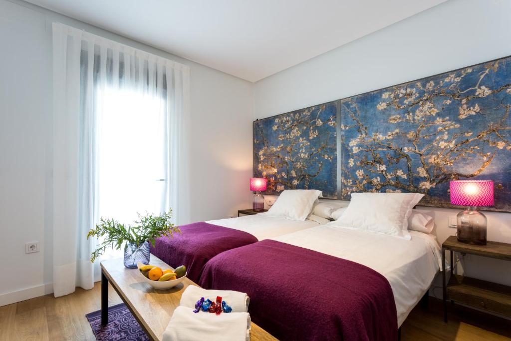 塞维利亚Apartamentos RG Plaza de España的卧室配有一张大床,墙上挂有绘画作品
