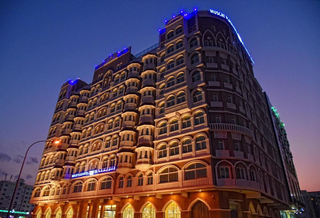 马斯喀特Muscat Plaza Hotel的一座高大的建筑,旁边灯火通明