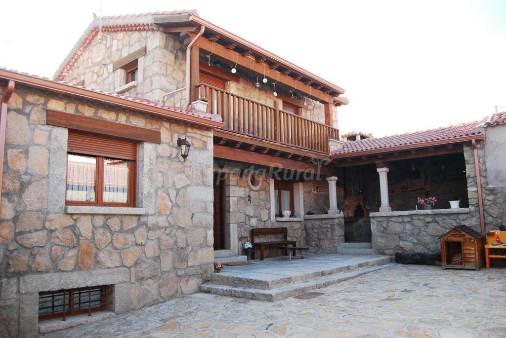 Muñogalindocasa rural La Gabina的石头房子设有阳台和庭院