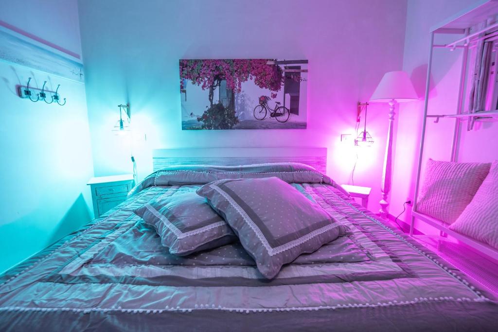 滨海波利尼亚诺B&B A Pochi Passi的一间卧室配有一张粉红色和蓝色的灯光床