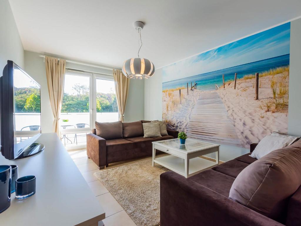 科沃布热格VacationClub - Aquarius Apartament 93的客厅配有沙发和海滩绘画