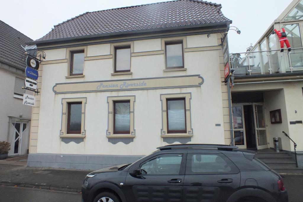 勒沃库森Pension Riverside in Leverkusen Hitdorf am Rhein - Zentral an der A1 und 59的停在大楼前的一辆黑色汽车