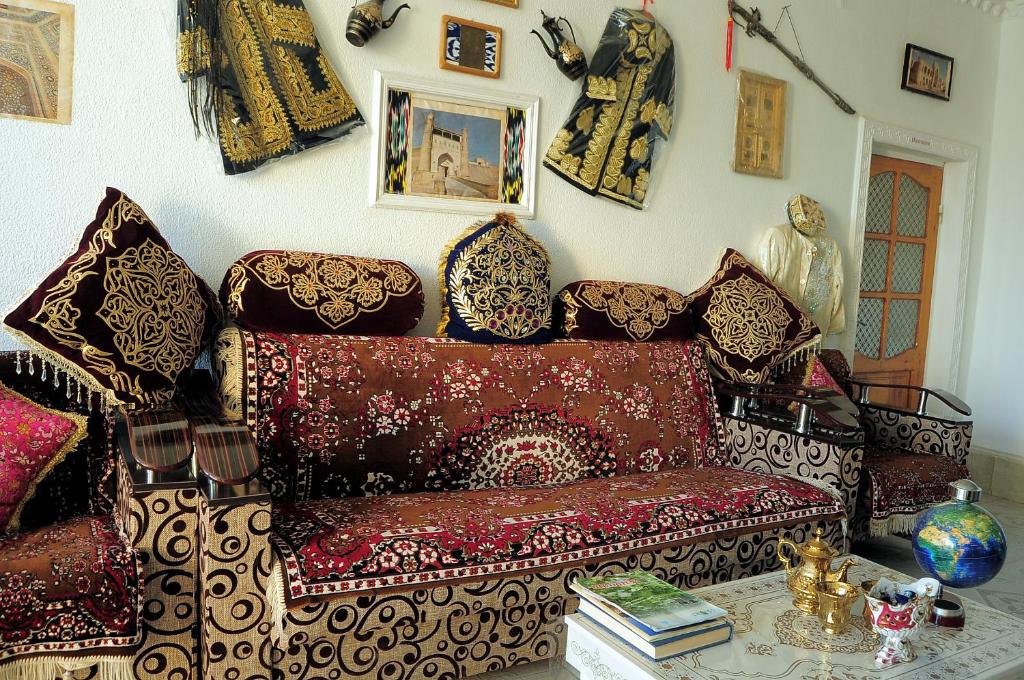 布哈拉Khan Rooms的客厅配有红色沙发和许多枕头