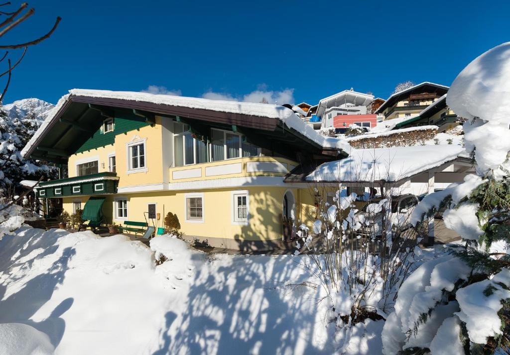 上柯尼希山麓米尔巴赫Apartment Lausbuam的雪中的一个黄色房子,有雪覆盖的树木