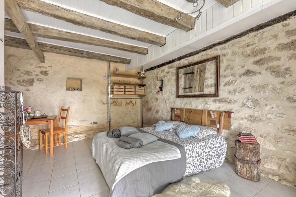 FarguesLe Mas des Papillons的卧室配有一张石墙内的大床
