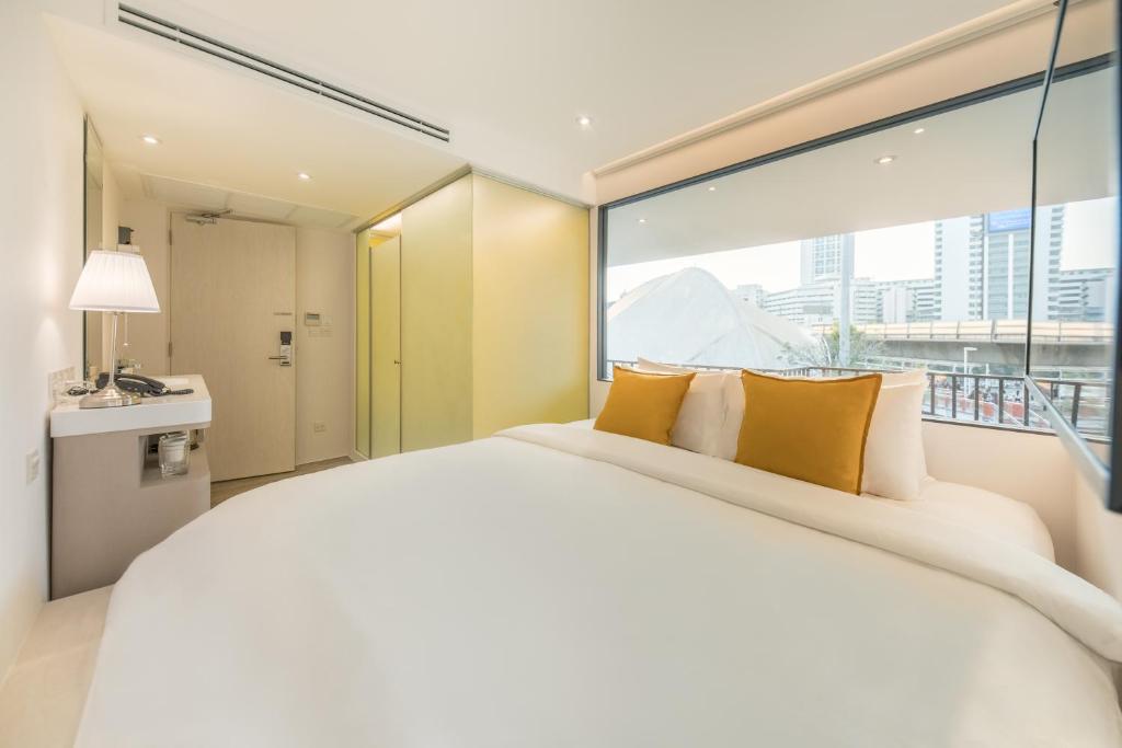 曼谷Yello Rooms Hotel Victory Monument的卧室设有一张大白色的床和大窗户