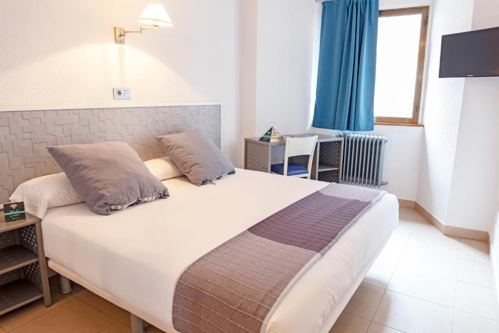 帕伦西亚阿尔达帕伦西亚中心酒店的卧室配有一张带蓝色窗帘的大型白色床