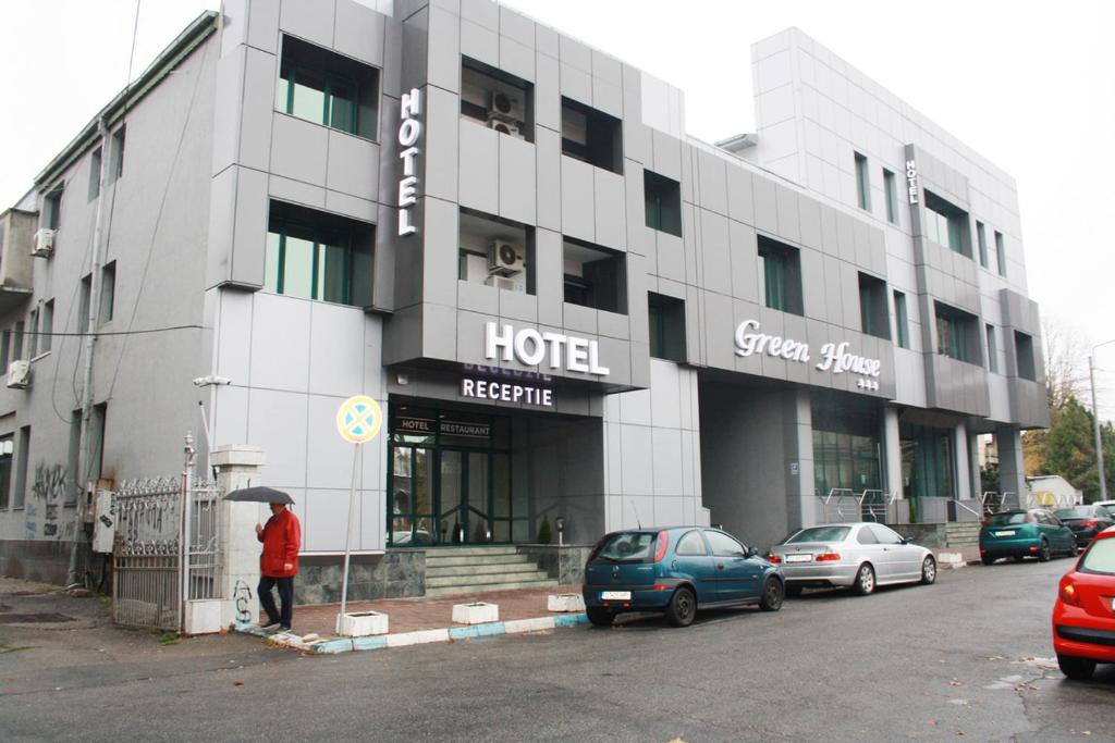 克拉约瓦Hotel Green House的站在酒店前的有雨伞的人