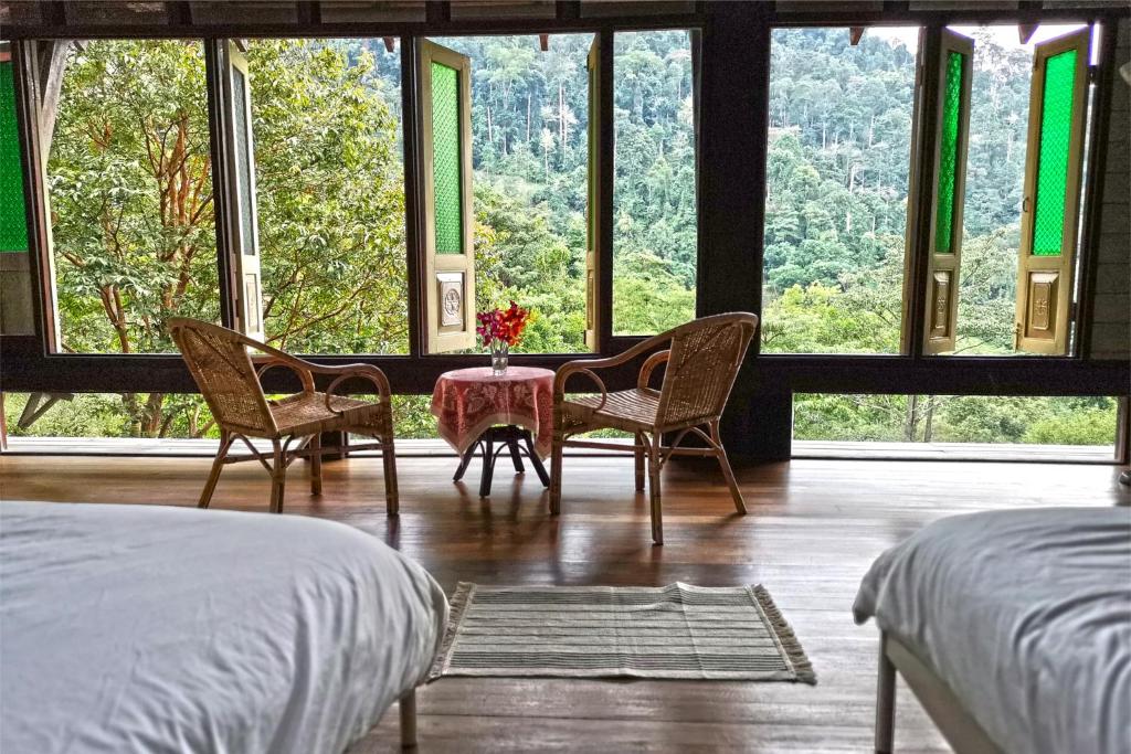 芙蓉Langit Rimba Resort的卧室配有两把椅子和一张桌子,位于窗户前
