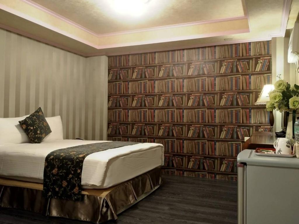 花莲市冠伦饭店的一间酒店客房,配有一张床和一堵书墙