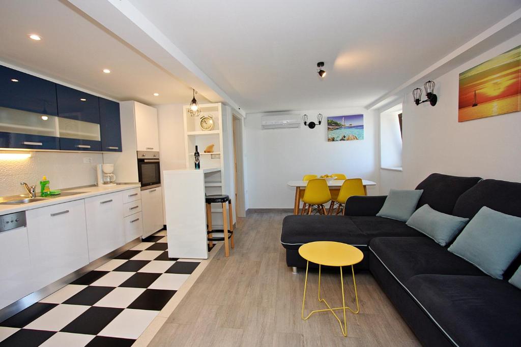 斯普利特卡Apartman Ivana的一间带黑色沙发的客厅和一间厨房