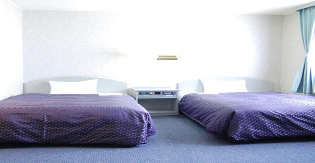 静冈Seagrande Shimizu Station Hotel / Vacation STAY 8209的紫色床单的客房内的两张床