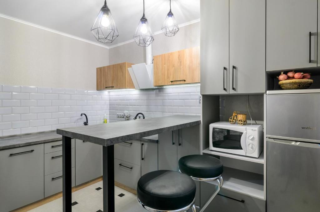 苏梅Greatest Luxury Apart-Hotel的厨房配有白色橱柜和带凳子的台面