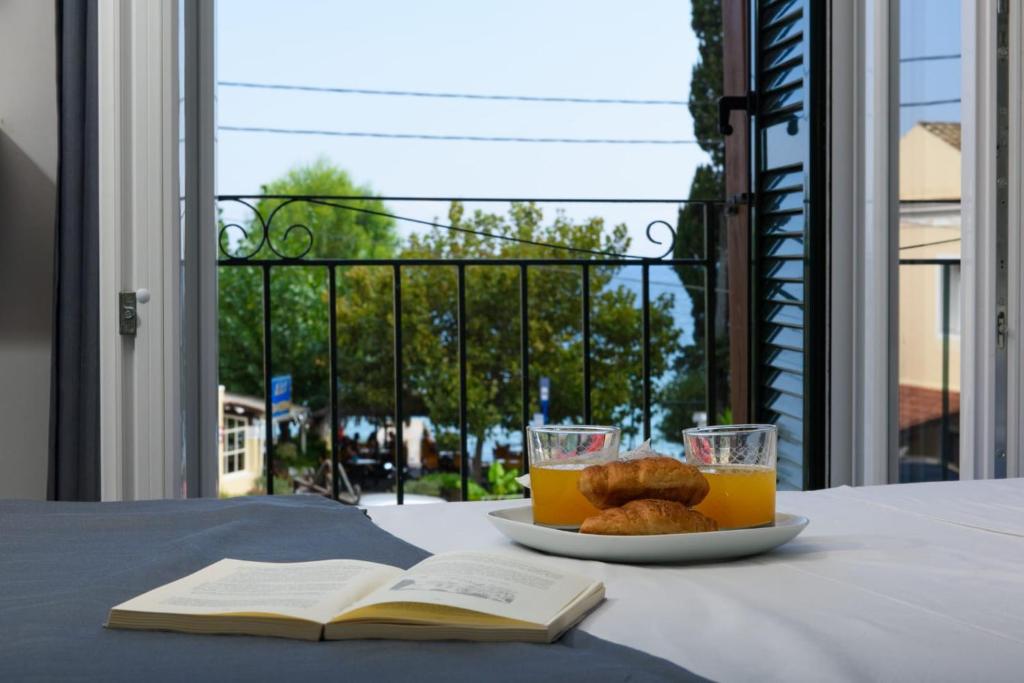阿普索斯Dorotea Luxury Rooms的桌上放着一盘橙汁和饼干,还有一本开放式的书