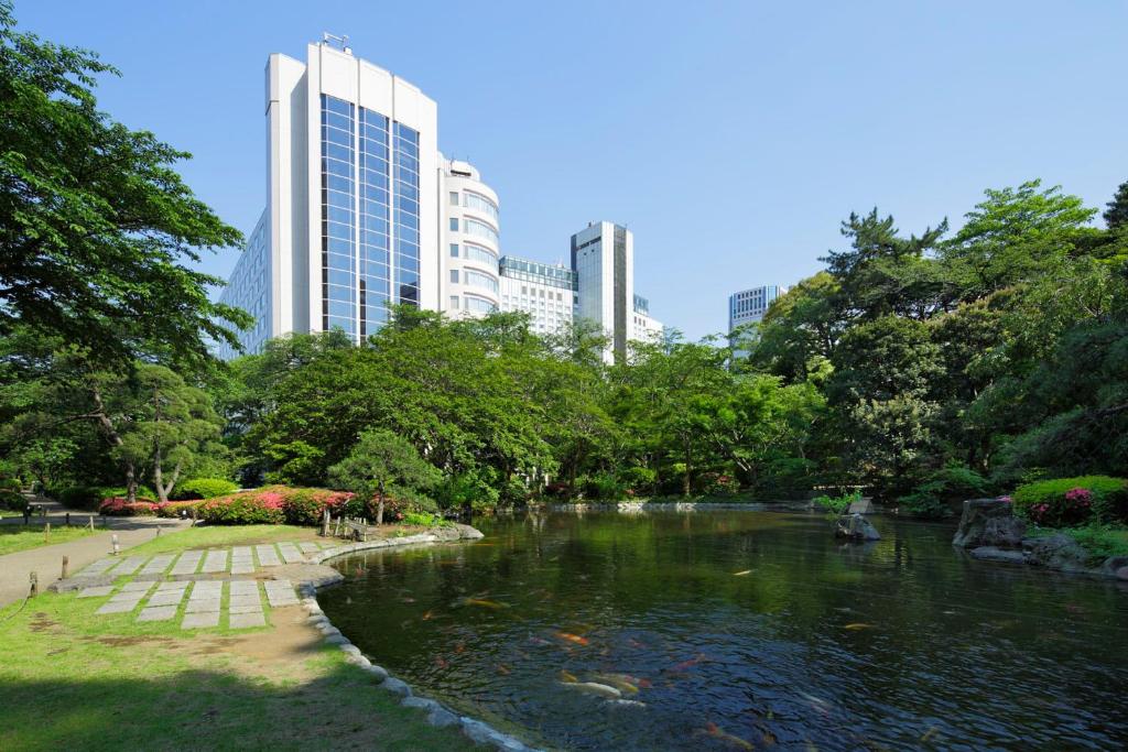 东京东京樱花塔王子大酒店的公园内一座池塘,有建筑背景