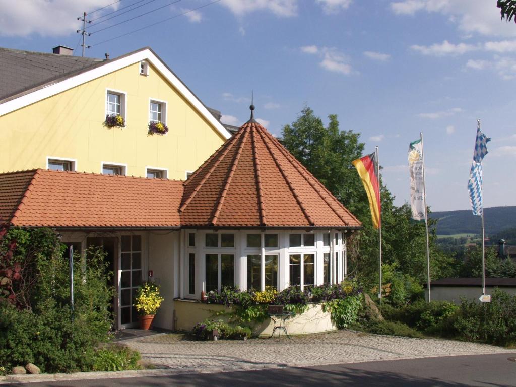 菲希特尔贝格WAGNERS Hotel Schönblick, C&C Hotels und Vertrieb GmbH的黄色房屋,设有瓷砖屋顶
