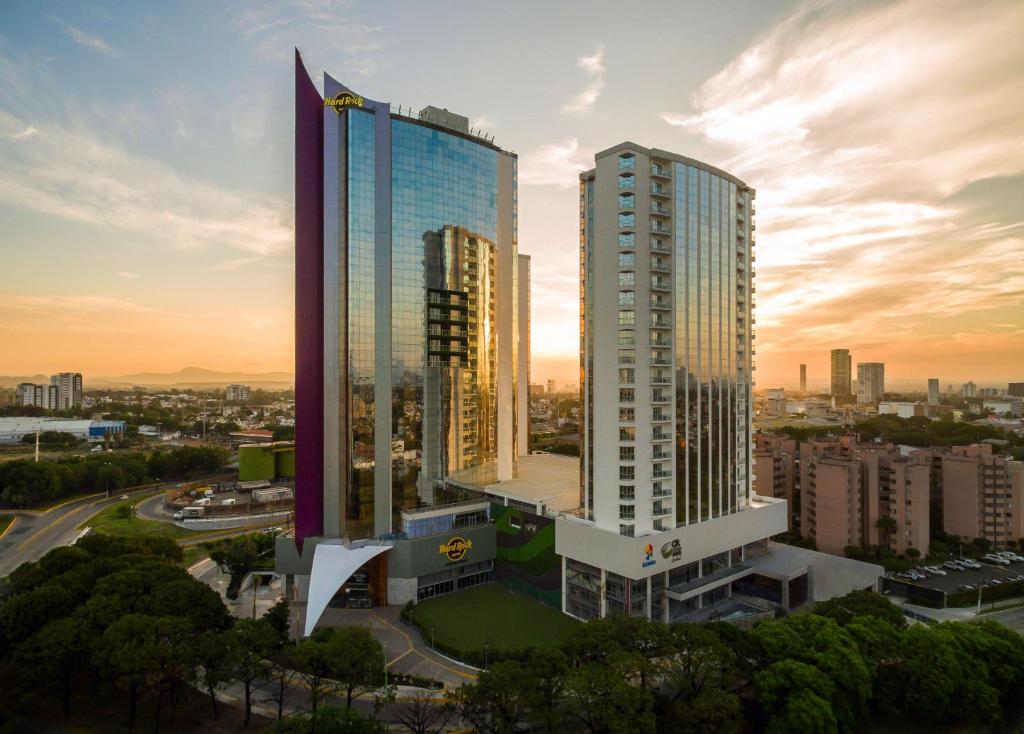 瓜达拉哈拉Hard Rock Hotel Guadalajara的日落时分城市的两座高楼