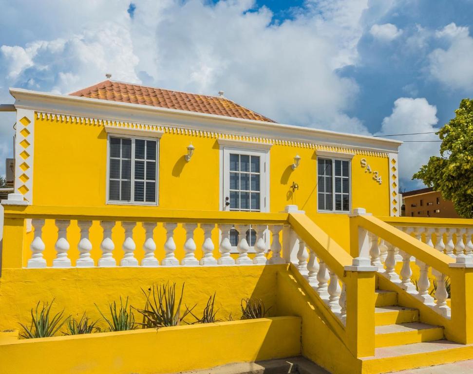 SavanetaOld Aloe House的黄色的房子,有白色的栅栏和楼梯
