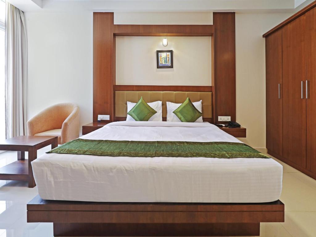 班加罗尔Treebo Trend Akshaya Bull Temple的一间卧室配有一张大床和一把椅子