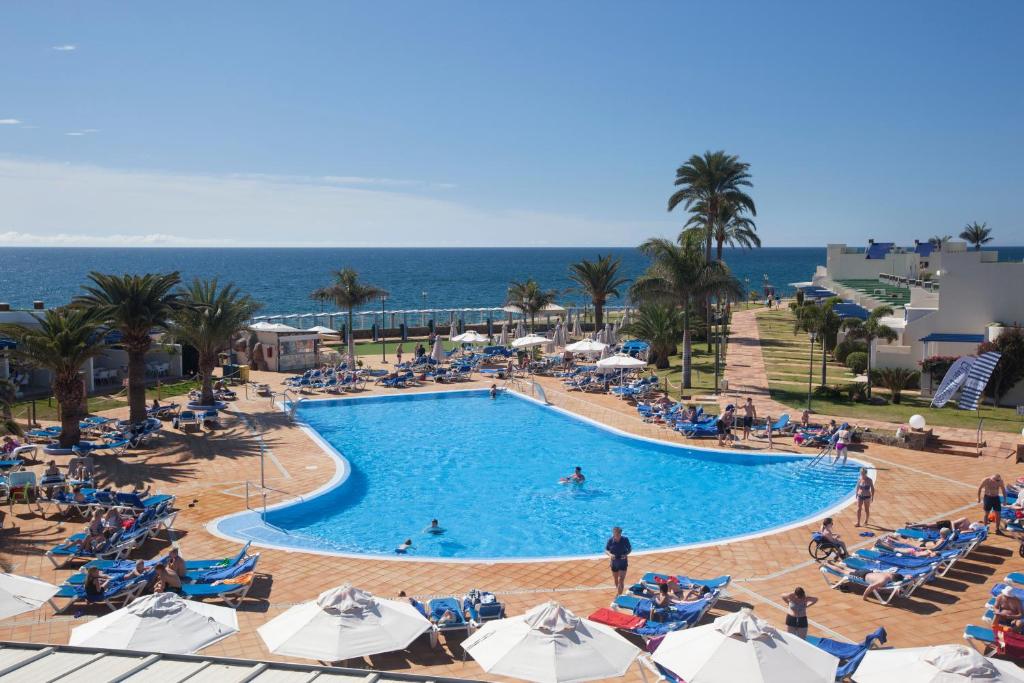 圣阿古斯丁Grupotel Playa Feliz的一座大型游泳池,里面设有椅子和大海