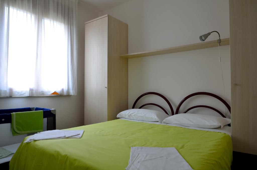 丽都阿德里亚诺奥罗拉住宅酒店的一间卧室设有一张绿色的床和一个窗户。