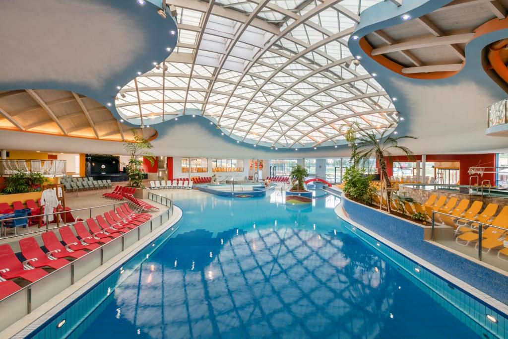 巴德瓦尔特斯多夫H2O Hotel-Therme-Resort, für Familien mit Kindern的一个带红色椅子和天花板的大型游泳池