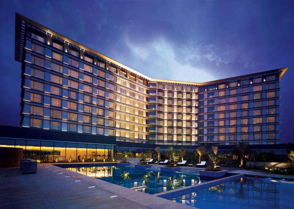 班加罗尔泰姬耶网普洱班加罗尔酒店的一座大型建筑,前面设有一个游泳池