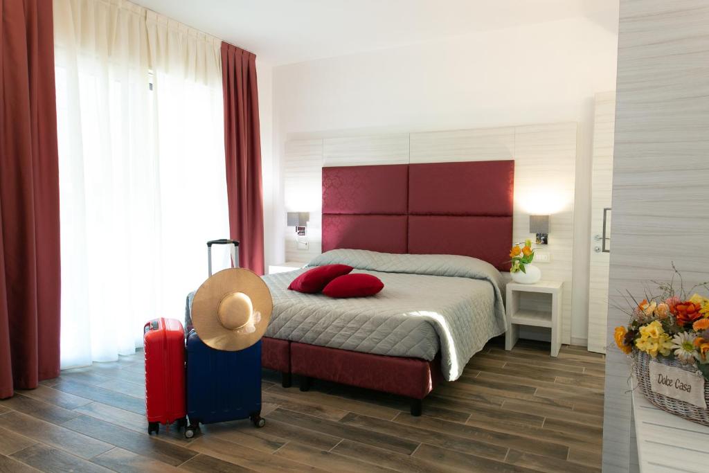 泰塞拉Guest House DOLCE LAGUNA 2的一间卧室配有一张带红色床头板和行李箱的床