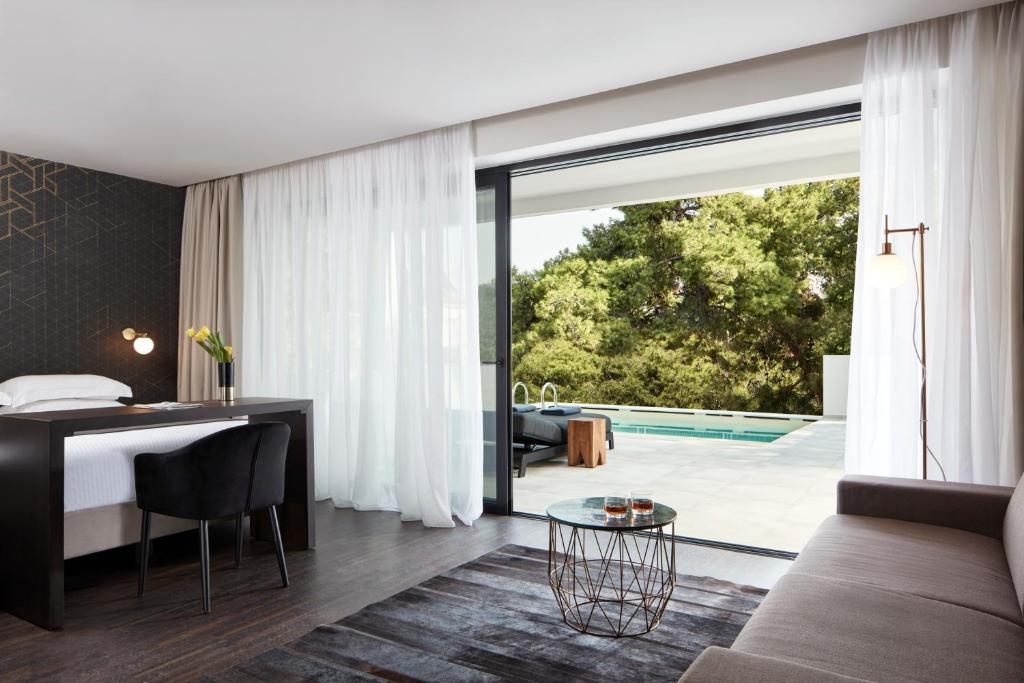 雅典Azur Hotel的一间卧室配有床、书桌和滑动玻璃门