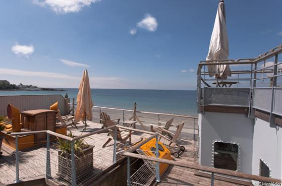 孔卡尔诺柯默尔酒店的海滩上带椅子和桌子的甲板