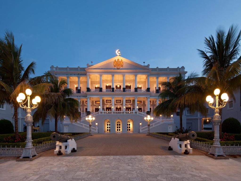 海得拉巴泰姬陵法拉克奴玛宫酒店的一座白色的大建筑,前面有棕榈树