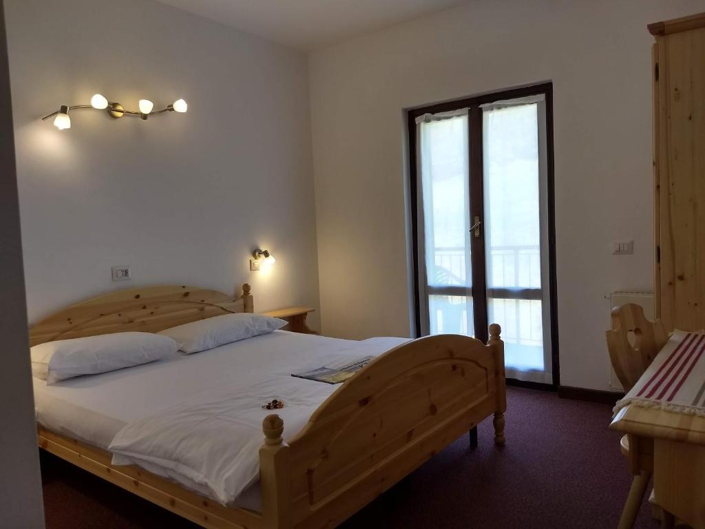 Taceno意大利餐厅萨西·罗西酒店的一间卧室设有一张木床和一个大窗户。