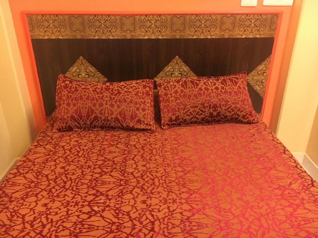 瓦拉纳西巴德拉卡利旅馆的一张带红色床罩和两个枕头的床