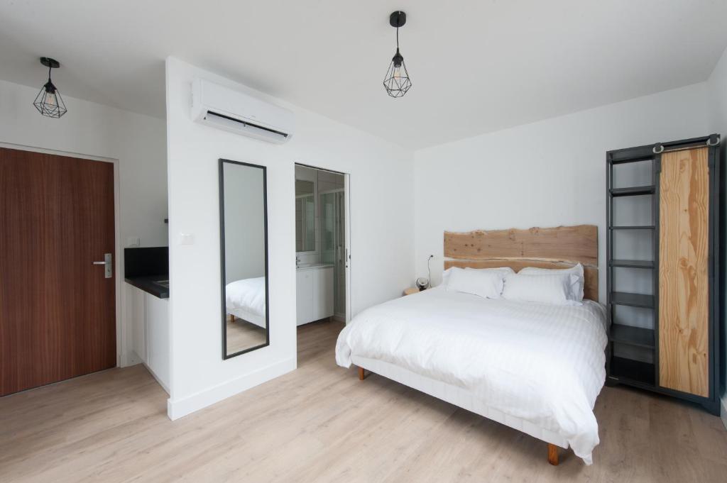 圣普斯特恩耶尔Le Jardin d Ambroise的卧室配有一张白色大床和镜子
