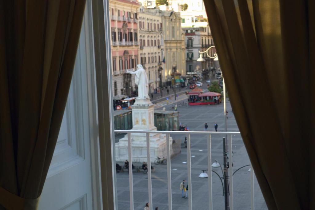 那不勒斯Il Viaggio di Dante Historical Center的从一扇带雕像的城市窗户欣赏风景