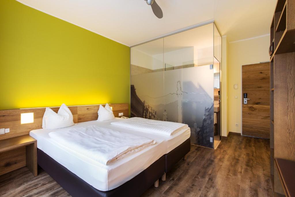 因斯布鲁克因斯布鲁克贝斯克酒店的一间卧室设有一张大床和黄色的墙壁
