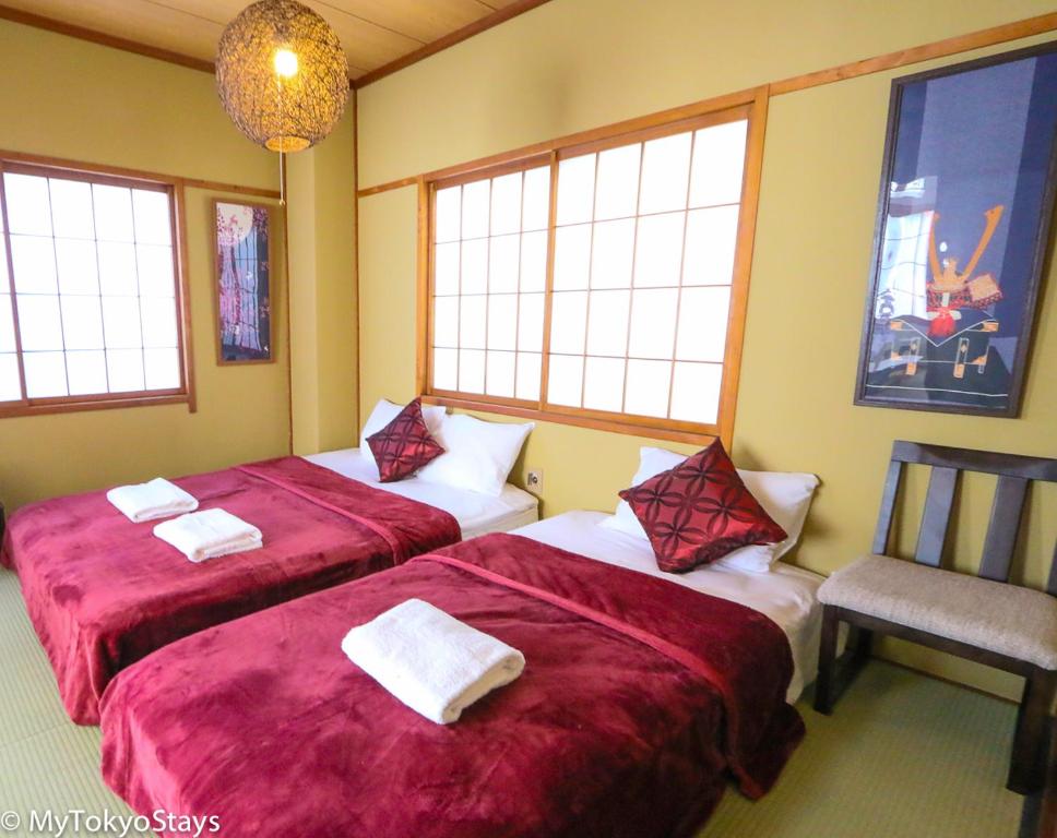 汤泽町和宿 湯沢チャオ的客房设有两张床、椅子和窗户。