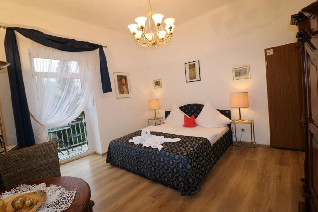 巴特基辛根琥珀别墅酒店的一间卧室设有一张床、一个窗户和一个吊灯。