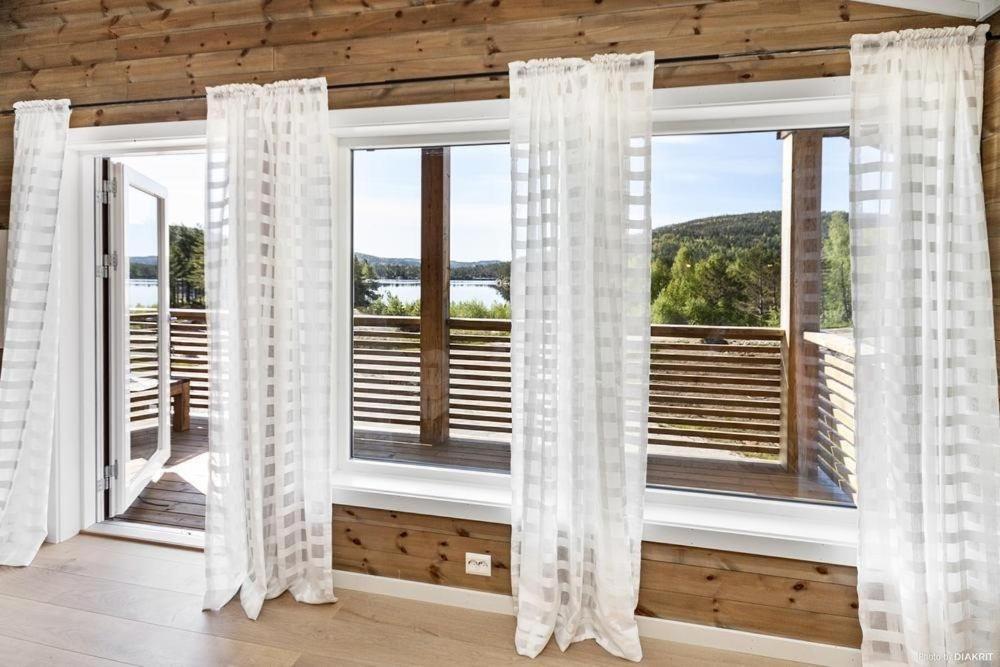 HornnesBjørndalsvatnet的客房设有带白色窗帘的大窗户。