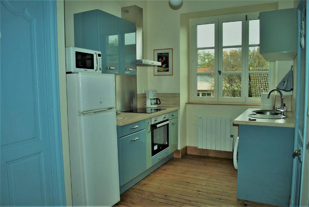 博讷Les Cimaises du Couvent的厨房配有蓝色橱柜和白色冰箱