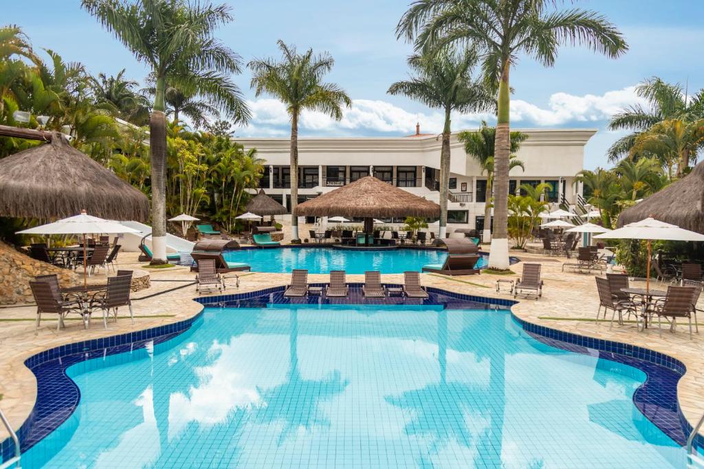 伊塔佩瓦Vale Suíço Resort的度假村的游泳池,配有椅子和遮阳伞