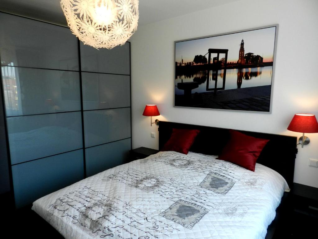 不来梅港Miramar的一间卧室配有一张带红色枕头的床和吊灯。
